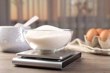 Dijital mutfak terazisi, bir kase şeker, kapalı masa, yakın plan.