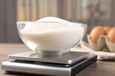 Dijital mutfak terazisi, bir kase şeker, kapalı masa, yakın plan.