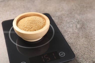 Dijital mutfak terazisi, gri masada bir kase şeker, yakın plan.