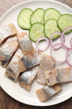 Lezzetli ringa balıkları, soğan ve salatalık dilimleri ahşap masa, üst manzara