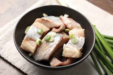 Tahta masada yeşil soğanlı lezzetli ringa balıkları, yakın plan.