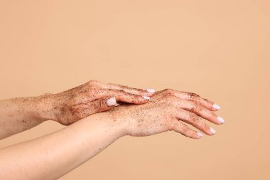 Bej arka planda ellerini ovuşturan kadın, yakın plan.