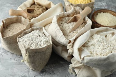 Gri desenli masa üzerinde farklı tipte un, yakın plan.