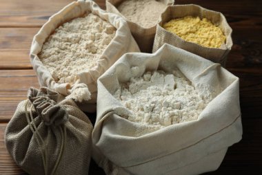 Tahta masadaki poşetlerdeki farklı un türleri, yakın plan.