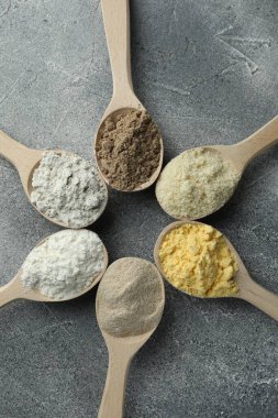Gri masadaki kaşıklarda farklı türde un, düz.