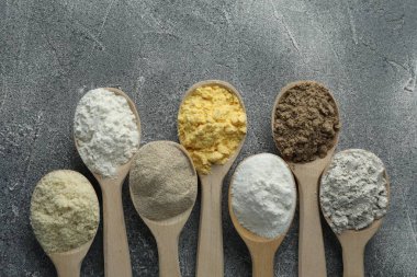 Gri masadaki kaşıklarda farklı türde un, düz.