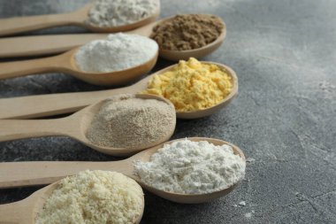 Gri masadaki kaşıklarda farklı türde un, yakın plan. Metin için boşluk