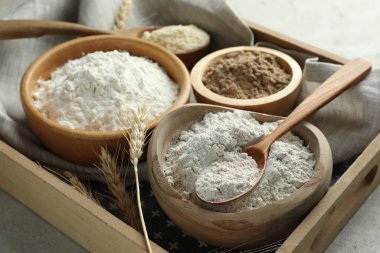 Açık gri masadaki farklı un türleri, yakın plan.
