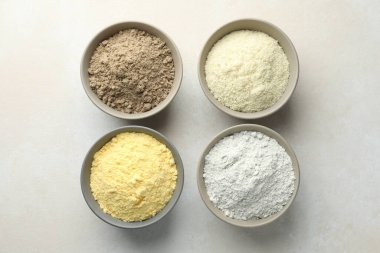 Açık gri masa ve düz tabaklar üzerinde farklı un türleri