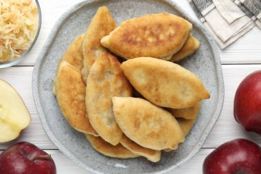 Lezzetli kızarmış pirizky (doldurulmuş turtalar) ve beyaz ahşap masa üzerinde elmalar, düz yatıyordu.