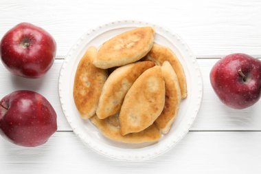 Lezzetli kızarmış pirizky (doldurulmuş turtalar) ve beyaz ahşap masa üzerinde elmalar, düz yatıyordu.
