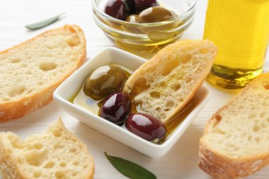 Beyaz ahşap masada yağlı ve zeytinli dilimler, yakın plan.