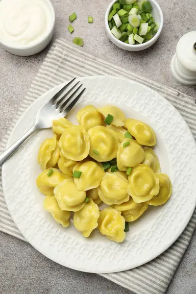 Taze soğanlı, tuzlu, ekşi kremalı ve çatallı lezzetli hamur tatlısı gri desenli masa, düz uzanma