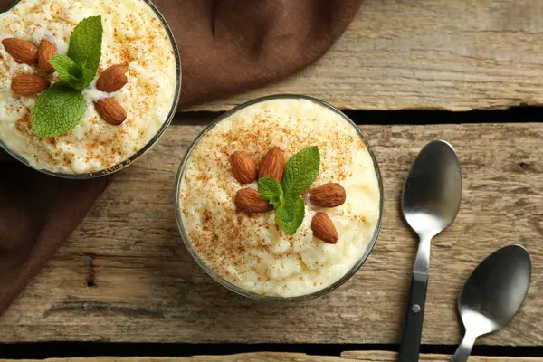 Tarçınlı lezzetli sütlaç, badem ve nane şekeri ahşap masada servis edilir.