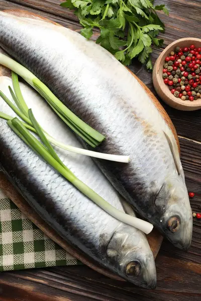 Tuzlu ringa balıkları ve baharatlar ahşap masada, düz yerde.