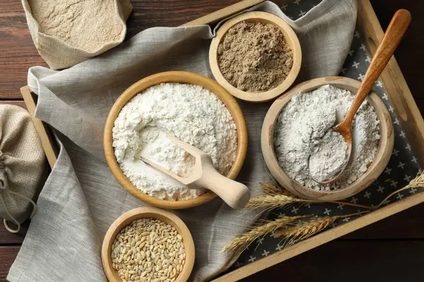 Tahta masadaki kaselerdeki farklı un türleri, düz uzanmış.