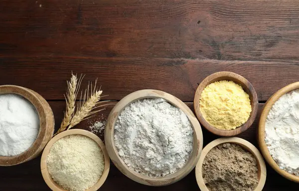 Tahta masadaki kaselerdeki farklı un türleri, düz yatış. Metin için boşluk