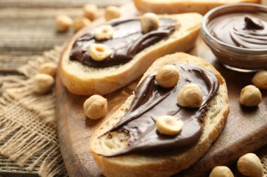 Çikolata sürülmüş ekmek dilimleri ve ahşap masada fındıklar, yakın plan.