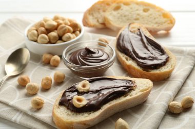 Çikolatalı ekmek dilimleri ve beyaz masada fındıklar, yakın plan.