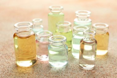 Bej desenli arka planda aromatik yağlı parfüm şişeleri, yakın plan.