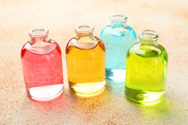 Bej desenli arka planda aromatik yağlı parfüm şişeleri, yakın plan.