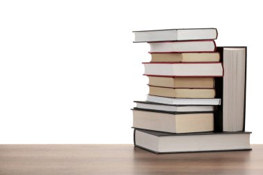 Beyaz arkaplana karşı ahşap masadaki eski kitaplar yığını