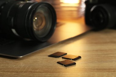 SD hafıza kartları, dizüstü bilgisayarlar ve fotoğraf makineleri ahşap masada, yakın plan.