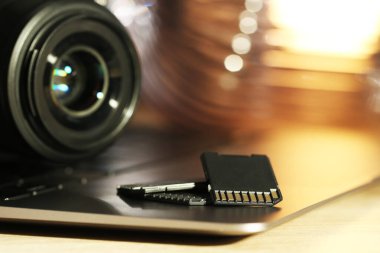 SD hafıza kartları, dizüstü bilgisayar ve fotoğraf makinesi masada, yakın plan.
