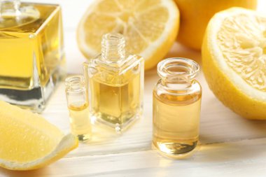 Aromatik esanslı parfüm şişelerini aç ve beyaz ahşap masada limon dilimleri, yakın plan.