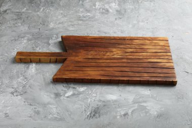 Açık gri desenli bir masada ahşap servis tahtası, yakın plan. Metin için boşluk