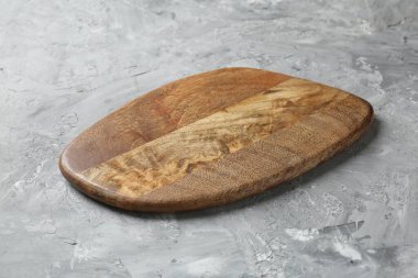 Açık gri desenli bir masada ahşap servis tahtası, yakın plan. Metin için boşluk