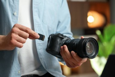 Bir adam fotoğraf makinesine SD bellek kartı yerleştiriyor.