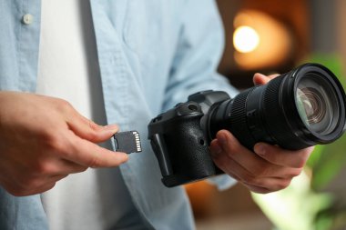 Bir adam fotoğraf makinesine SD bellek kartı yerleştiriyor.