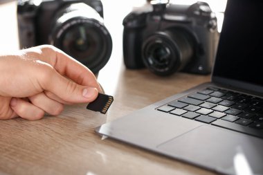 SD bellek kartını bilgisayarın içine yerleştiren adam ahşap masa, yakın plan