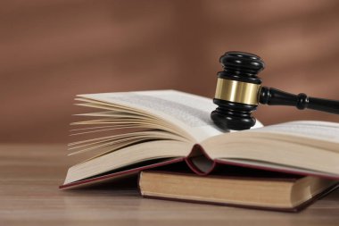 Hakimin tokmağı ve kitapları ahşap masada, kahverengi arka planda, yakın plan.