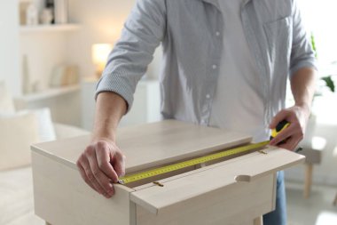 İçerideki bantla ahşap dolabı ölçen adam, yakın plan.