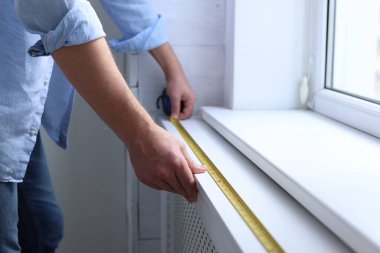 Pencere pervazını bantla ölçen adam, yakın plan.