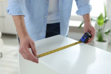 Beyaz rafları bantla ölçen adam içeride, yakın plan.