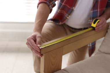 Koltuğunu bantla ölçen adam, yakın plan.