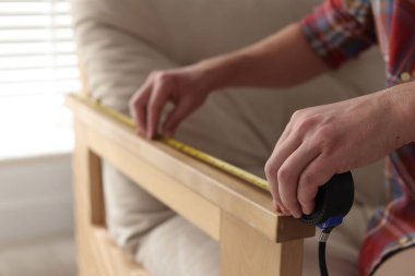 Koltuğunu bantla ölçen adam, yakın plan.