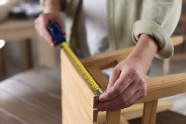 İçerideki bantla ahşap tabureyi ölçen adam, yakın plan.