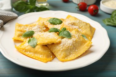 Peynirli ve fesleğenli leziz ravioli açık mavi ahşap masa, yakın plan.