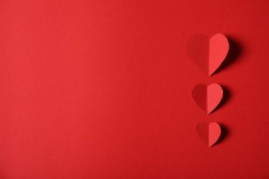 Kırmızı arka planda bir sürü kağıt kalp var. Metin için boşluk