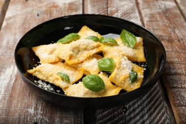 Ahşap masada parmesan peynirli ve fesleğenli lezzetli ravioli, yakın plan.