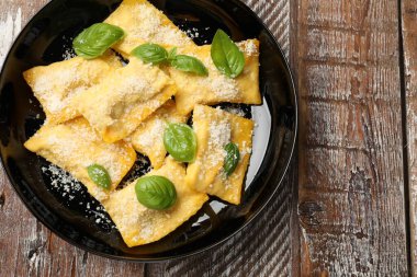 Ahşap masada parmesan peynirli ve fesleğenli lezzetli ravioli.