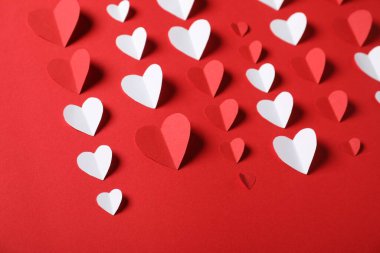 Kırmızı arkaplanda bir sürü kağıt kalp, yakın plan