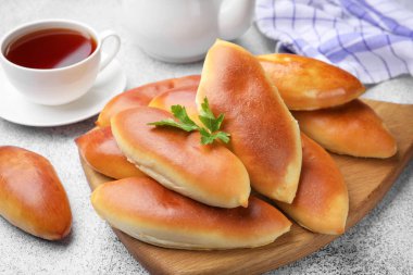 Lezzetli fırında köfteler ve bir fincan çay. Gri desenli masa, yakın plan.