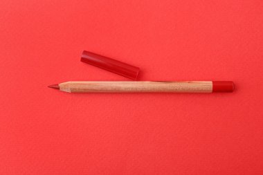 Kırmızı arka planda güzel bir dudak kalemi, üst manzara.