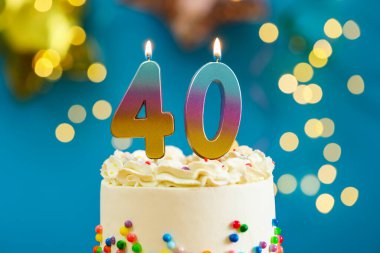 40. yaş günü. Pastanın üzerinde yanan mumlar arka planda bulanıklık yaratıyor. Işıklar, yakın plan. Bokeh etkisi