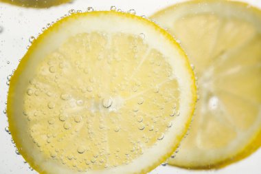 Arka planda limon dilimleri olan soda, yakın plan.